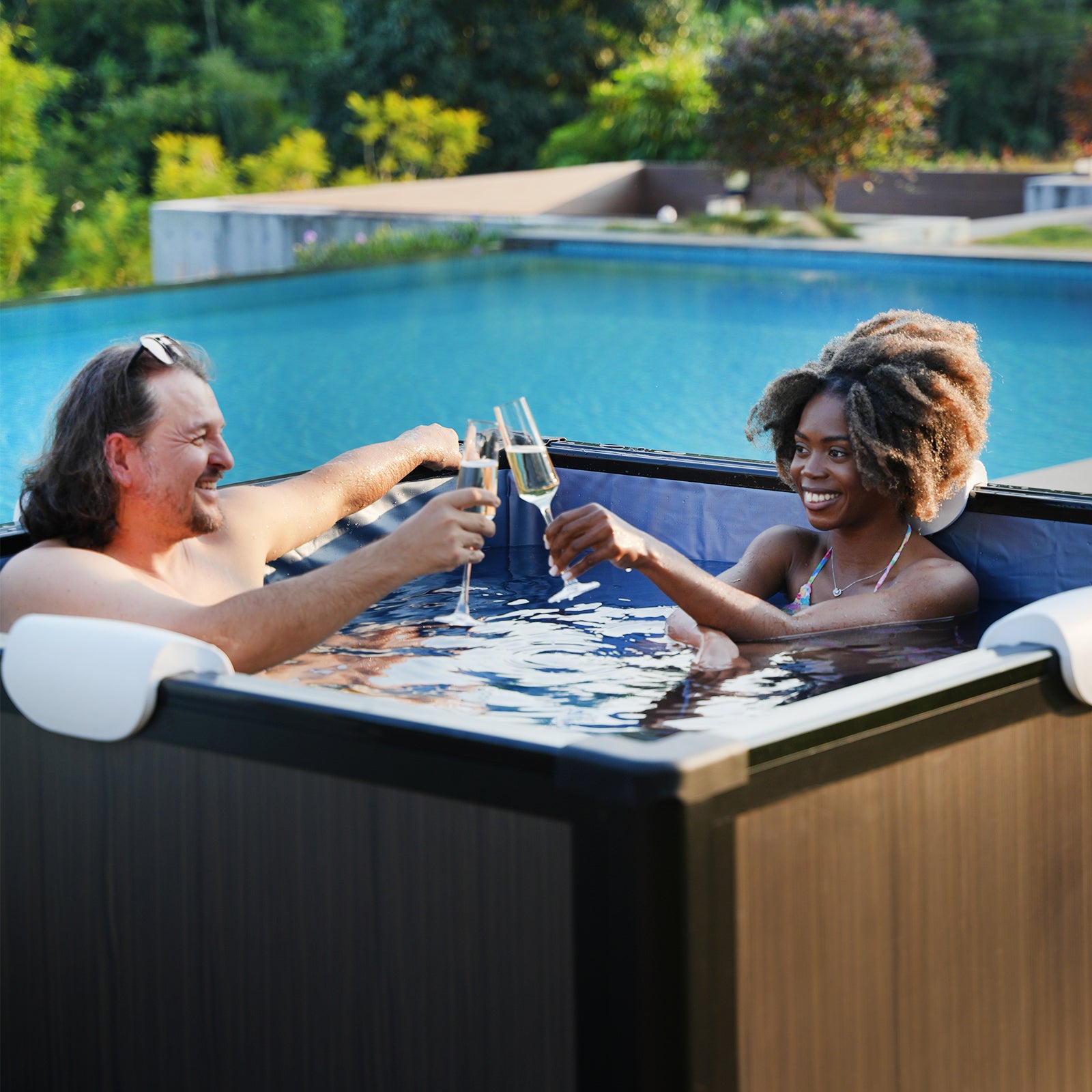 Couple relaxing in Relxtime aluminum frame hot tub outdoors with champagne